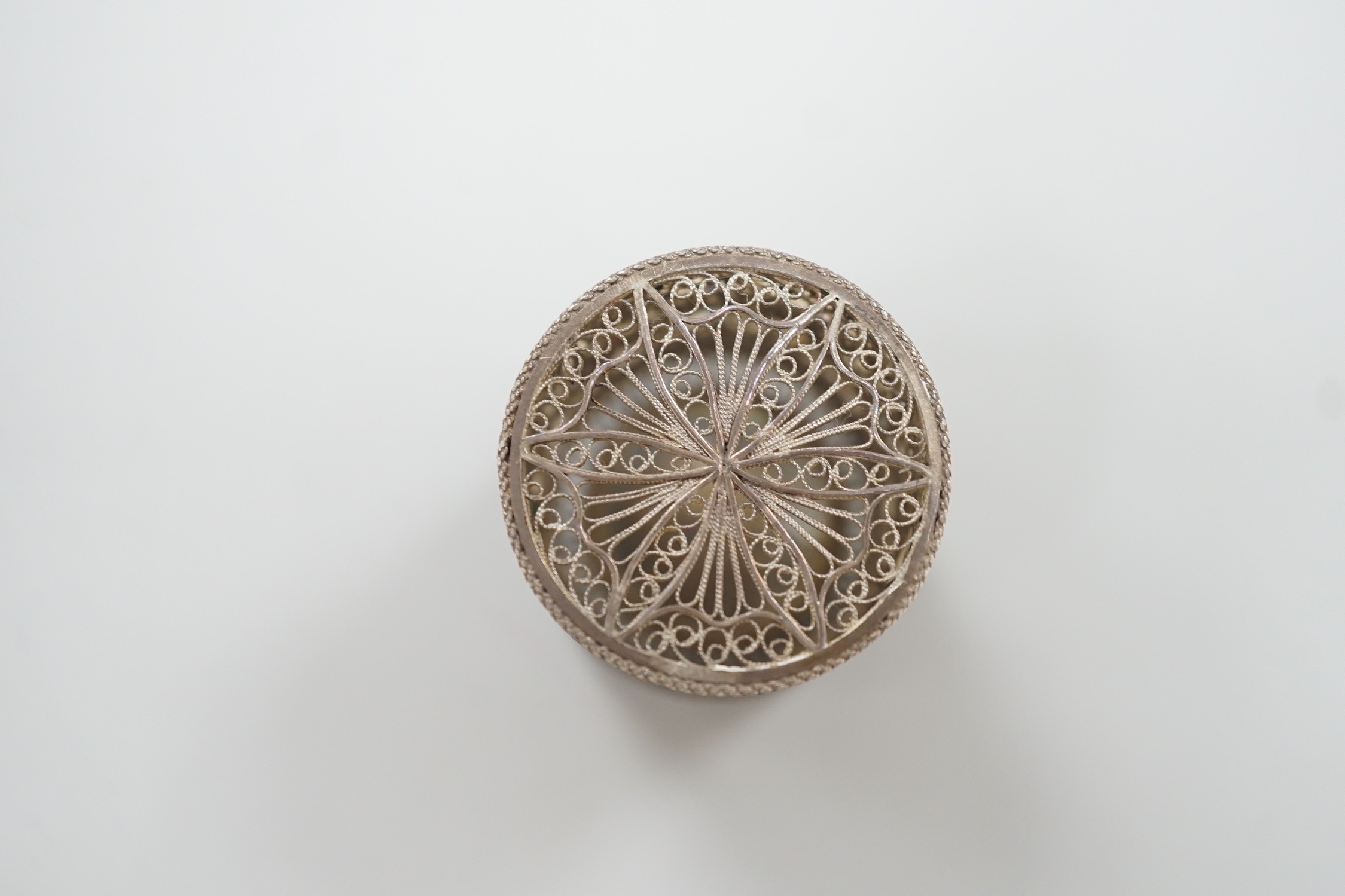 A continental filigree white metal and enamelled cylindrical pill box, the cover enamelled with a picture playing card, height 32mm.